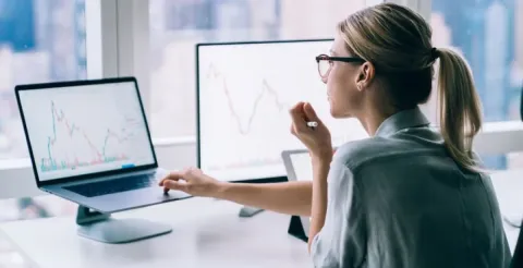 Woman analysing financial graphs and statistics on computer