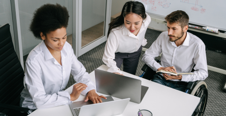Three people in an office setting looking at laptop screens. 