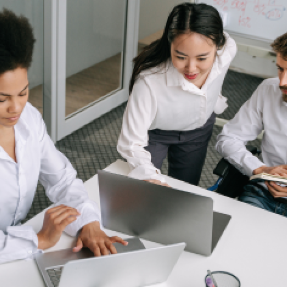 Three people in an office setting looking at laptop screens. 